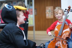 Wauwatosa West Orchestra Sophomore student Keeler Hick teaches a child how to play a cello at Wauwatosa West’s 21st annual Kinderkonzert on December 7th.
