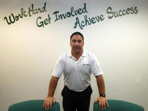 West Principal Frank Calarco stands in front of the inscription on the wall of his office after being first appointed as Principal. Calarcos friend painted the inscription in his office to stress this message to students. 