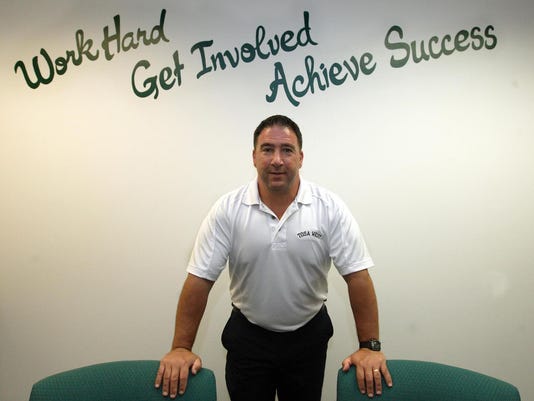 West Principal Frank Calarco stands in front of the inscription on the wall of his office after being first appointed as Principal. Calarco's friend painted the inscription in his office to stress this message to students. 