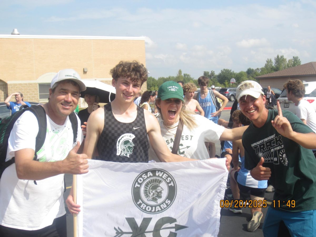 All coach Cady, coach Schnieder, and coach Maggie taking a picture with 10th place varsity runner Mitchell Schmitt at Muskego Sept 20th 2025